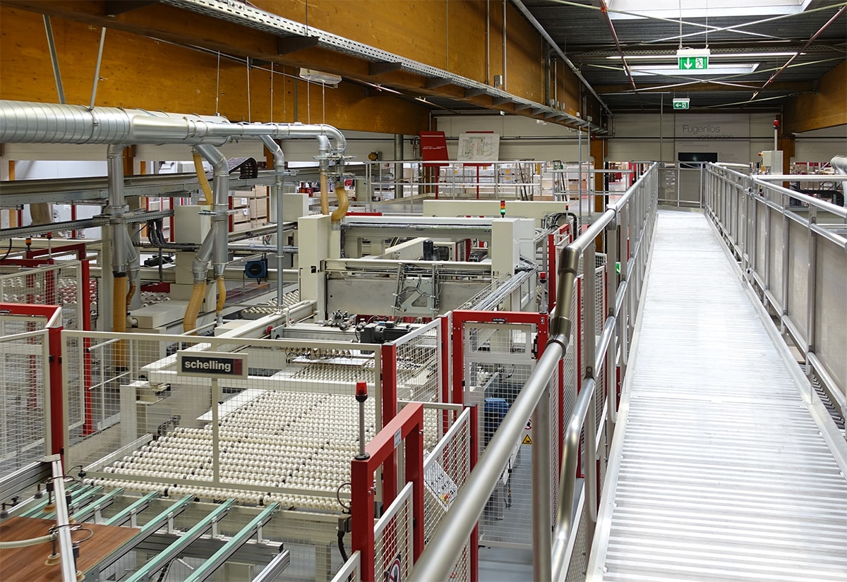 Innenansicht einer Produktionshalle mit automatisierten Maschinen und Förderanlagen zur Fertigung.